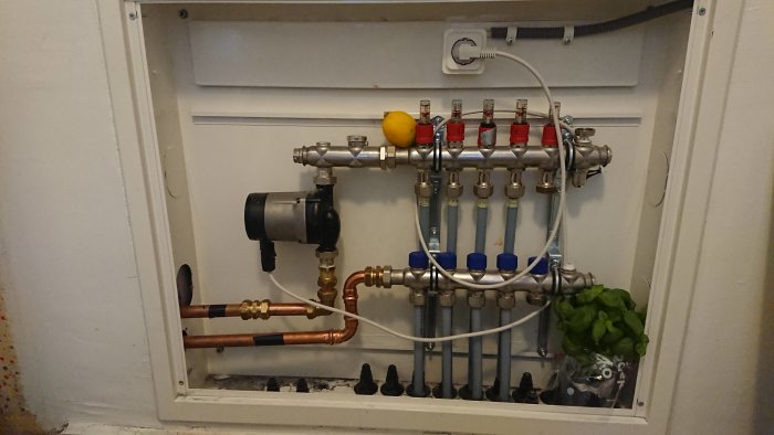 Värmesystem med rör och ventiler dekorerat med en citron och en basilikaplanta.