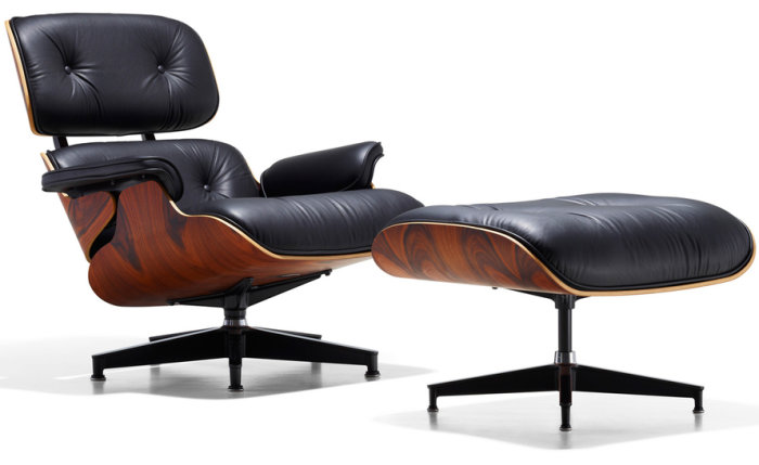 Eames Lounge Chair med Ottoman i svart läder och valnötsfanér på vit bakgrund.