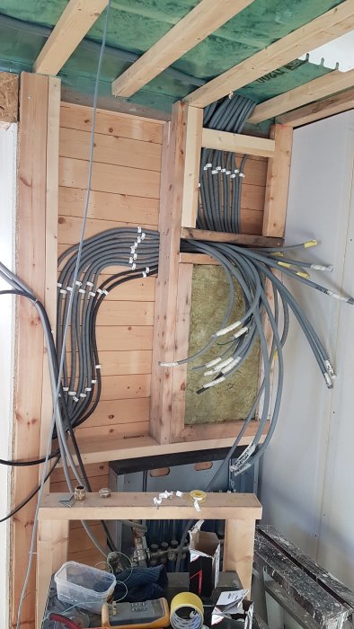 Installation av elektriska kablar och rör på en träkonstruktion inne i en byggnad.