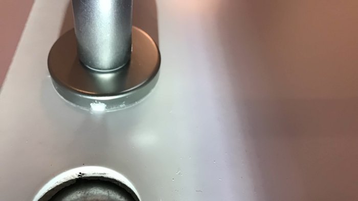 Närbild på dörrhandtag utan synliga skruvar, med litet hål vid basen som kan vara för en dold fästanordning.