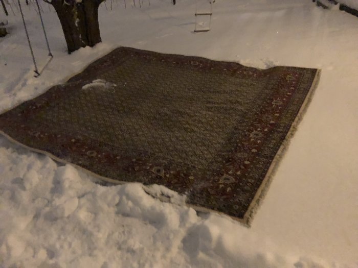 Orientalisk matta ligger i snön ute på natten.