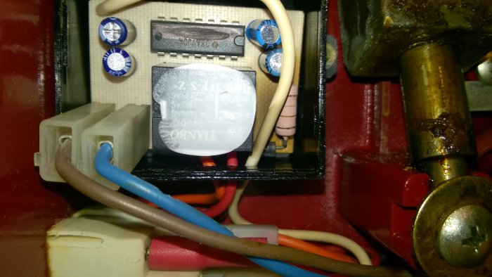 Inre komponenter i en skärmaskin inklusive en kondensator, elektriska kopplingar och ledningar.