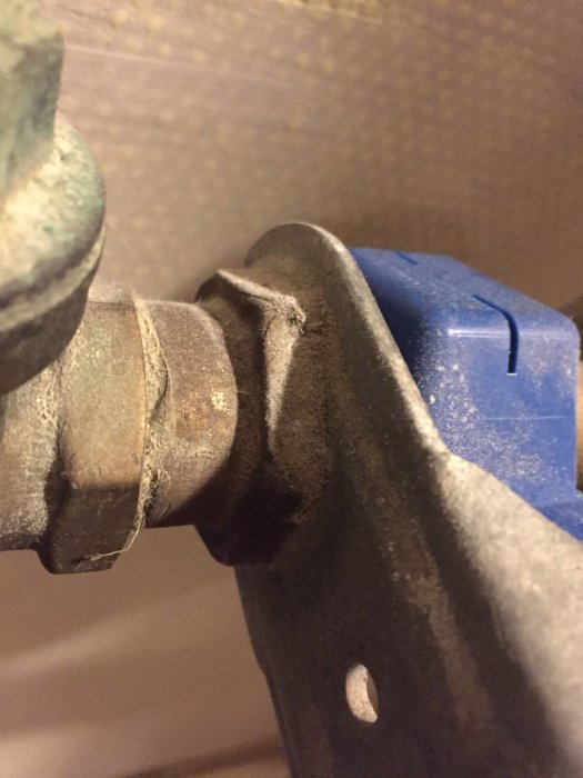Närbild på tjocka muttrar som sitter på en bult med blått plastdetalj i bakgrunden.