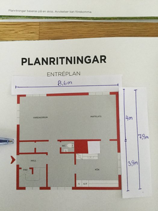 Planritning av entréplan i hus, med handskrivna måttangivelser och en penna som pekar på en position.