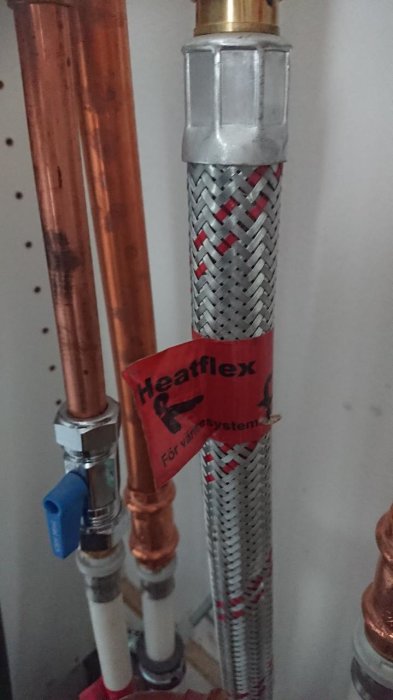 Rörledningar för värme med klistermärke "Heatflex För värmesystem" och en flexibel slanganslutning.