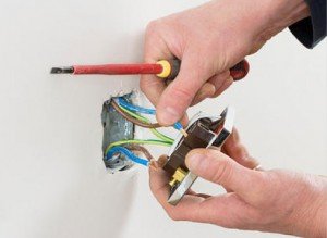 En person installerar en strömställare med synliga ledare och kopplingsklämmor.