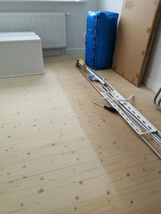 Grangolv i ett rum med tydlig nyansskillnad där möbler tidigare stått, verktyg och byggmaterial syns också.