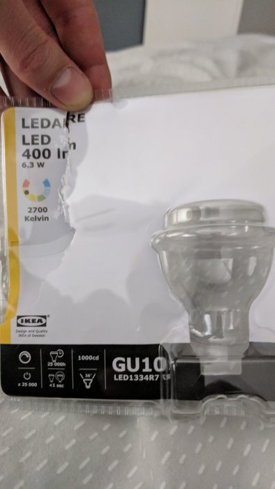 Hand håller en IKEA LEDARE LED-lampa i förpackning med GU10-sockel och specifikationer synliga.