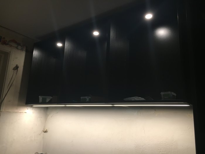 Installation av bänkbelysning och takspottar i ett kök med tända ljuskällor som inte kan styras separat.