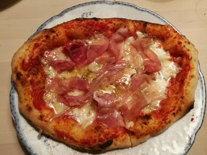 Hemlagad pizza med gorgonzola, buffelmozzarella, parmesan och parmaskinka på rustik tallrik.