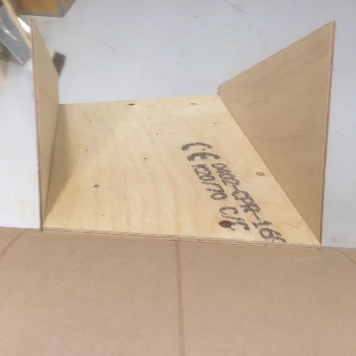 Hörndel av en träkonstruktion med släta och fasade kanter i olika vinklar, förmonterad för att passa en cyklonspåntratt.