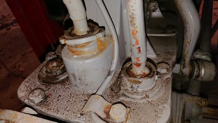 En lös övre mutter på en maskindel med synlig rost och smuts.
