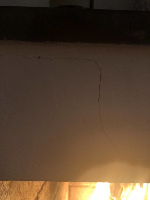 Spricka i överkanten på en öppen eldstad, upplyst av svagt eldsken.