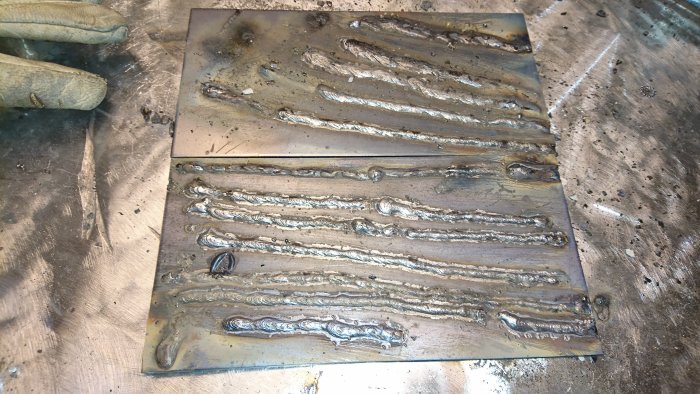En ojämn svetsövning med flera svetssträngar på ett metallbord i en svetsstation.