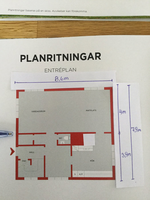 Planritning över en lägenhets entréplan med mått, visar ett kök, hall, WC och vardagsrum.