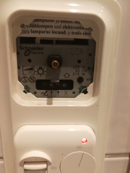 Öppen ELJO dimmerbrytare som visar interna komponenter och justeringsinställningar på väggen.