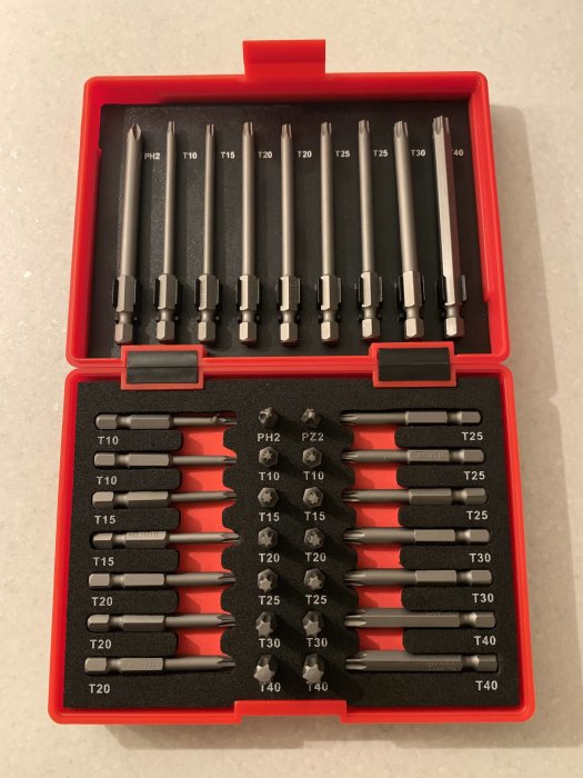 Ett uppsättning nya långa bits i olika storlekar och former för skruvdragare, förpackade i en röd låda.