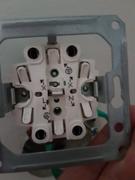 Ett öppet eluttag utan frontplatta där kablarna ska lossas för installation av distansringar.