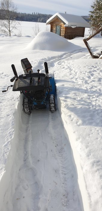 Cotech DB 7655 snöslunga på 6,5 hk rensar snö, visar tydlig gångväg i snön framför ett timmerhus.