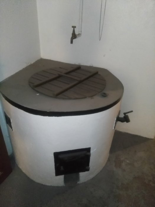 En gammal tvättgryta av gjutjärn med lock i en tvättstuga.