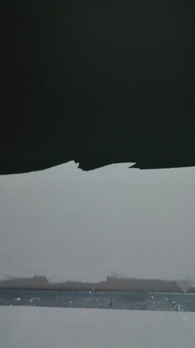 Målarfärg som flagnar och lossnar i flikar från en väggyta.