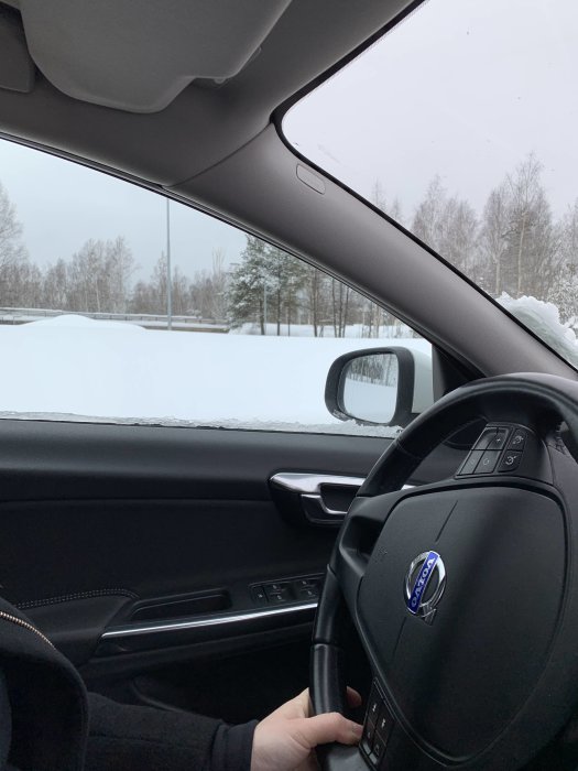 Vy från förarsidan av en bil som visar en snötäckt påfart under en viadukt i Norrland.