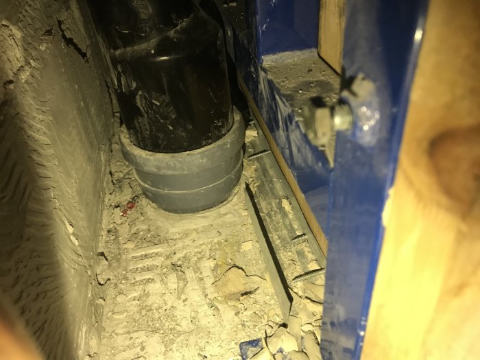 Öppet utrymme bakom vägghängd WC utan tydligt tätskikt synligt, rörarbete och otäta ytor.
