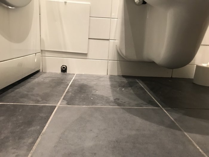 Bild på toalettgolv och vägghängd WC utan synligt skvallerrör eller tätskikt, möjlig fuktskada tecken.