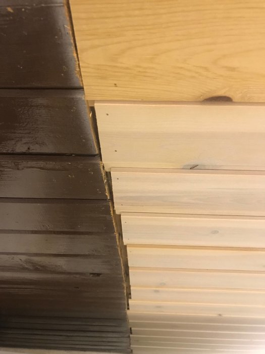 Delvis öppet golv i köket visar mörkt knarrande parkett och ljusare träplank bredvid, åtgärd efter tidigare vattenläcka.