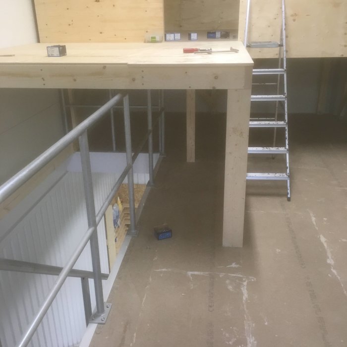 Byggplats där en ny trappa konstrueras, med plywoodgolv och markerade stegpositioner vid ett loft.
