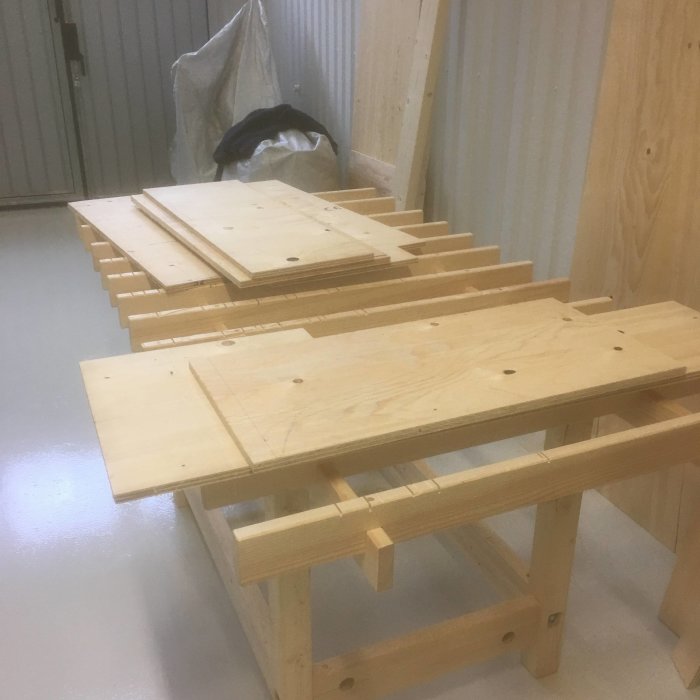 Träkonstruktion och plywooddelar förberedda för montering av en skräddarsydd trätrappa.