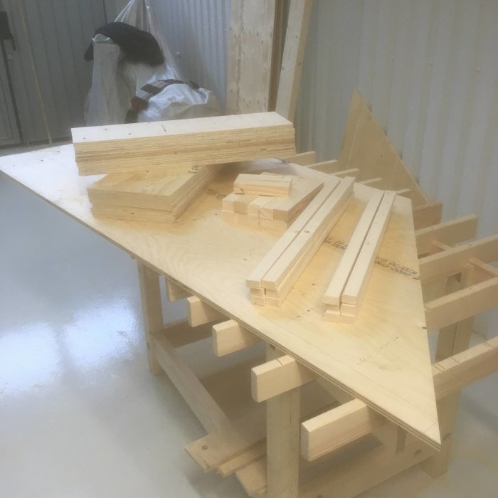 Trädelar som är förberedda för trappbygge, upplagda på ett arbetsbord i en verkstad.