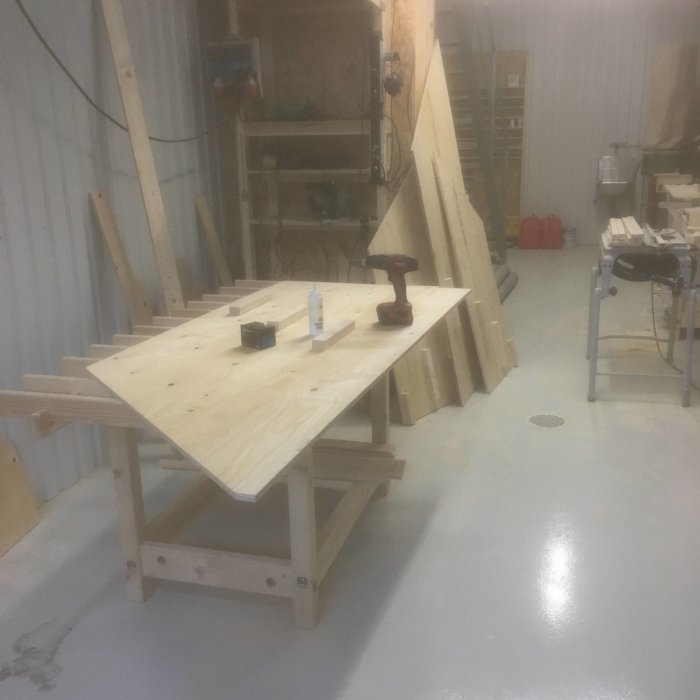 Verkstadsbild med arbetsbänk, verktyg och pågående trappkonstruktion med träbitar.