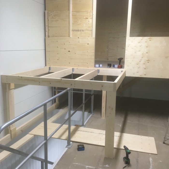 Obyggt lofttrappstomme i trä med ribb-bänk och ramverk för golv, omgiven av skyddsplattor och verktyg.