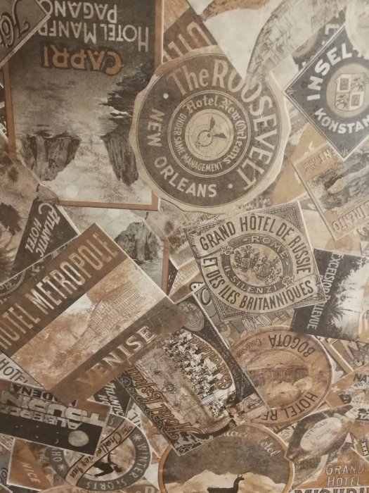 Vägg klädd med collage av vintage reseaffischer och hotellreklam.