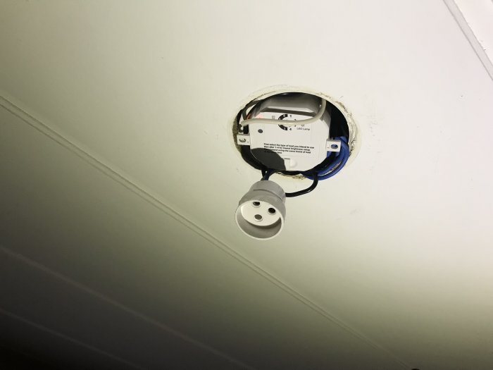 Takinstallationslåda med öppen dosa och vajerklämma, samt en oansluten elektrisk sockel som hänger löst.