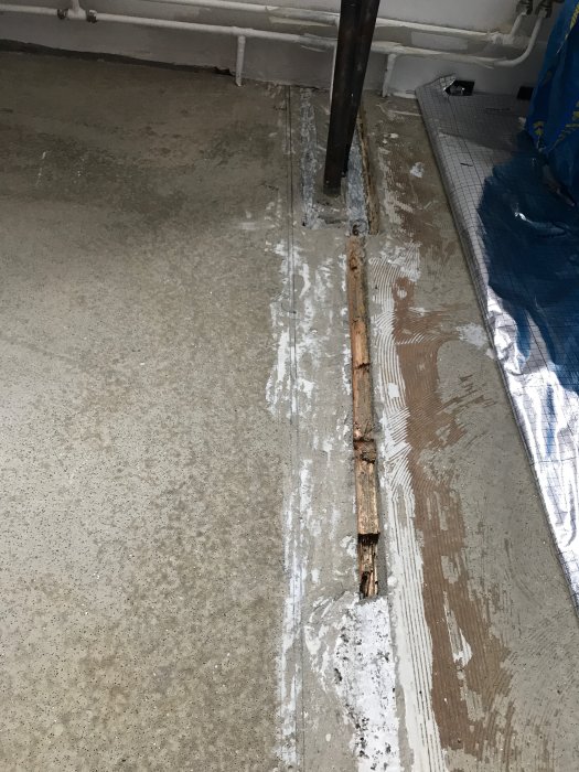 Golv under renovering med synlig träskarv och ojämnheter där tidigare glasvägg varit.