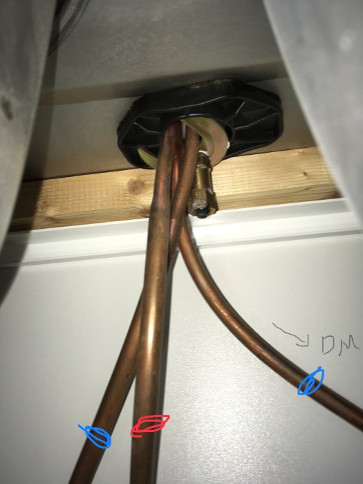 Röranslutningar under diskbänk med märkningar som visar koppling till diskmaskin.