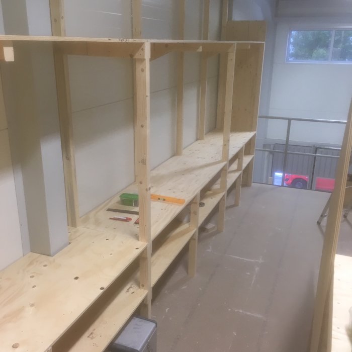 Nybyggd lagerhylla i trä med arbetshylla och förvaringsutrymme under, och verktyg på hyllan.