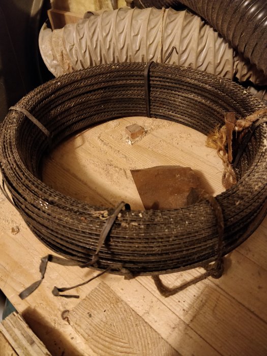 Rulle med oanvänd, sammansatt ståltråd liggandes på en träyta.