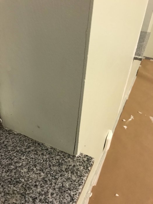 En spricka i ett hörn mellan två målade innerväggar ovanför en granitbänkskiva.