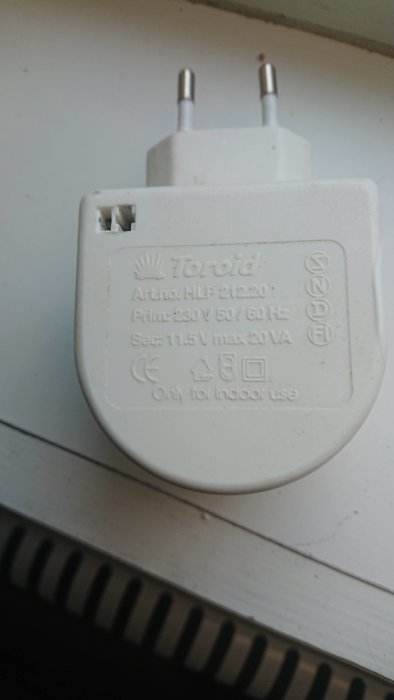 Vit batterieliminator med specifikationer: Prim 230V 50Hz, Sec 11.5V max 20VA, märkt med CE och för inomhusbruk.