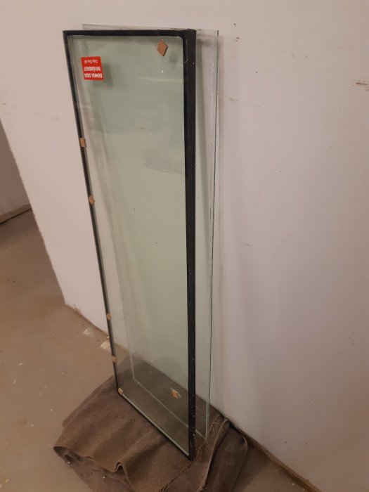 En ny treglasruta står lutad mot en vit vägg, synligt tjockare än en enkelglasruta.