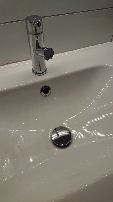 Handfat med kromad blandare och Prevex vattenlås synligt mot vit porslinsyta.