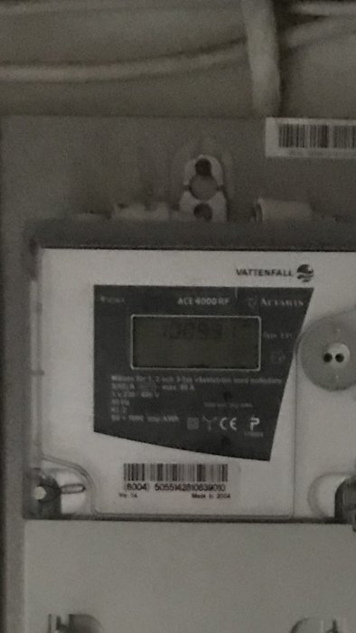 Otydlig bild av en Vattenfall elektrisk mätare modell ACE6000 RF med skärmen som visar siffror.