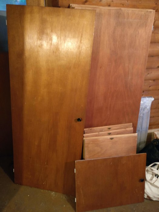 Fyra olika storlekar av gamla träskåpluckor står lutade mot en vägg, eventuellt teak, bortskänkes.