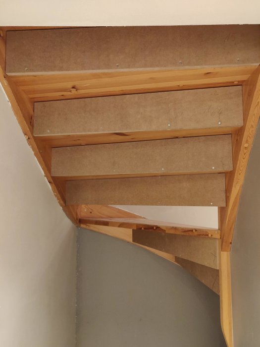 Trappa under renovering med MDF-skivor skruvade mot trappsteg, synlig glipa ovanför.