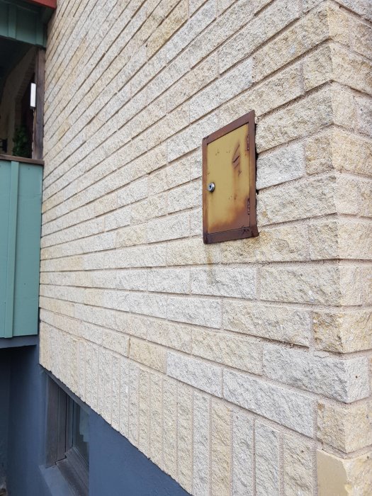 Rostigt elskåp på en tegelvägg, kablar syns inte men används för att diskutera elsystemet i huset.