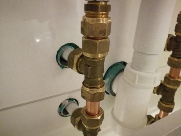 Vattenrör och kopplingar utan silikonfog där de går in i badrumsväggen.
