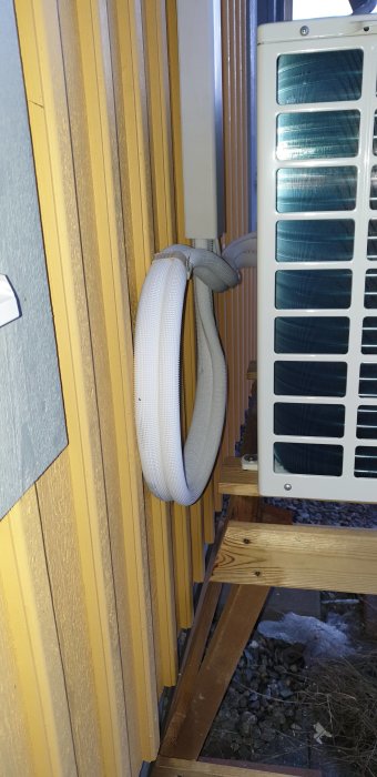 Ny Innova värmepump installerad på gul vägg med synliga slangar/rör i loopen utan rörkapningsverktyg.